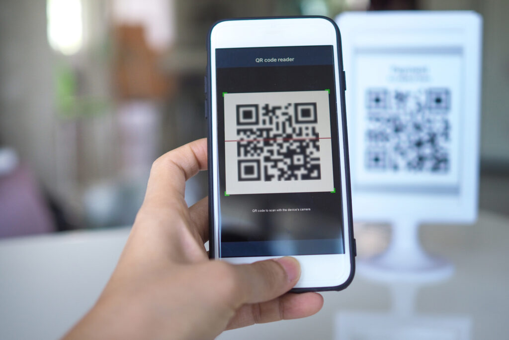 A person holding a smartphone with a QR code on the screen. QR codes help in facilitating accessibility for people who are blind or have low vision.