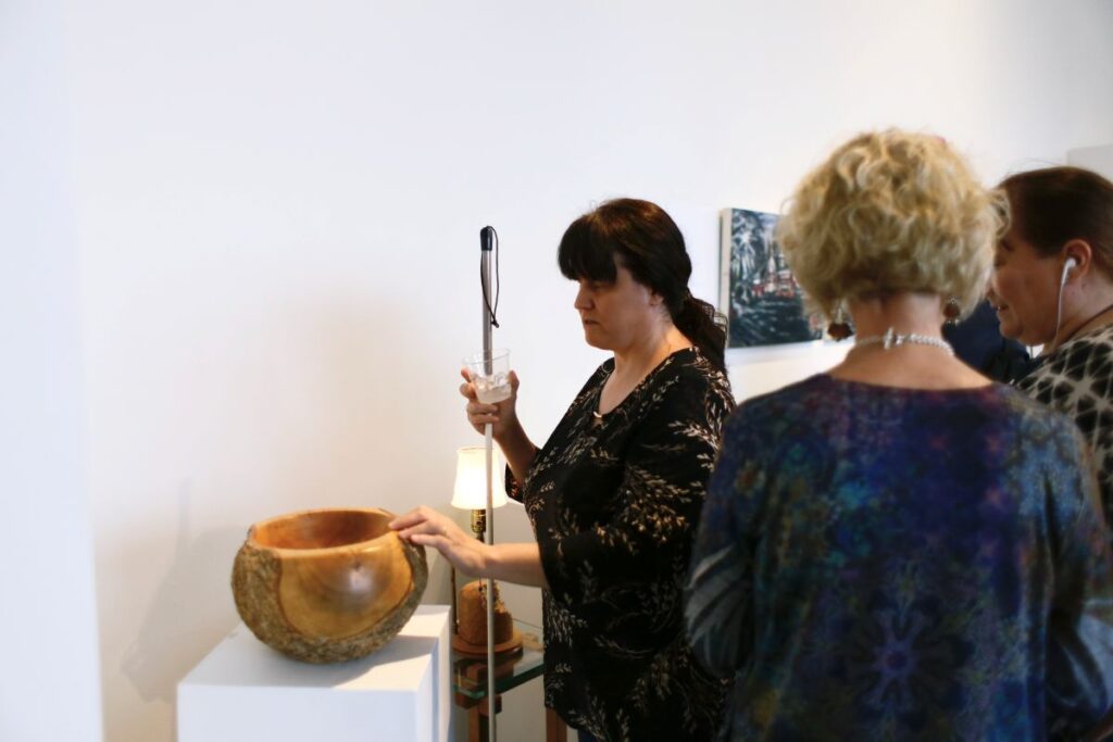 Dr. Cheryl Fogle-Hatch touching "White Ash Burl Bowl with Bark On” carved by George Wurtzel in 2019. Photo by Christine Qabar