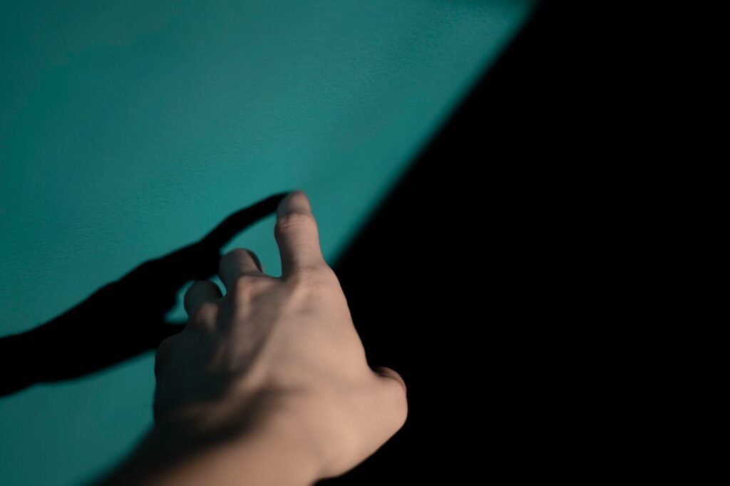 A hand reaches toward a textured surface, index finger about to touch it.